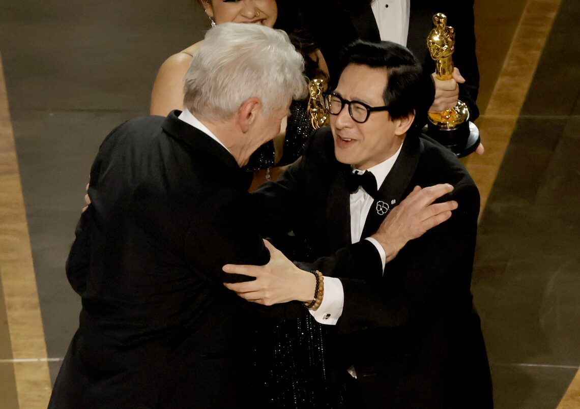 Ke Huy Quan accepts the award for Best Picture for "Everything Everywhere All at Once" from Harrison Ford onstage during the 95th Annual Academy Awards.
