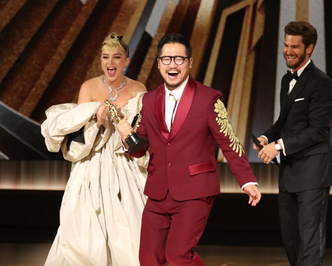 Daniel Kwan (R) accept the Best Original Screenplay award for "Everything Everywhere All at Once" from Florence Pugh and Andrew Garfield onstage during the 95th Annual Academy Awards.