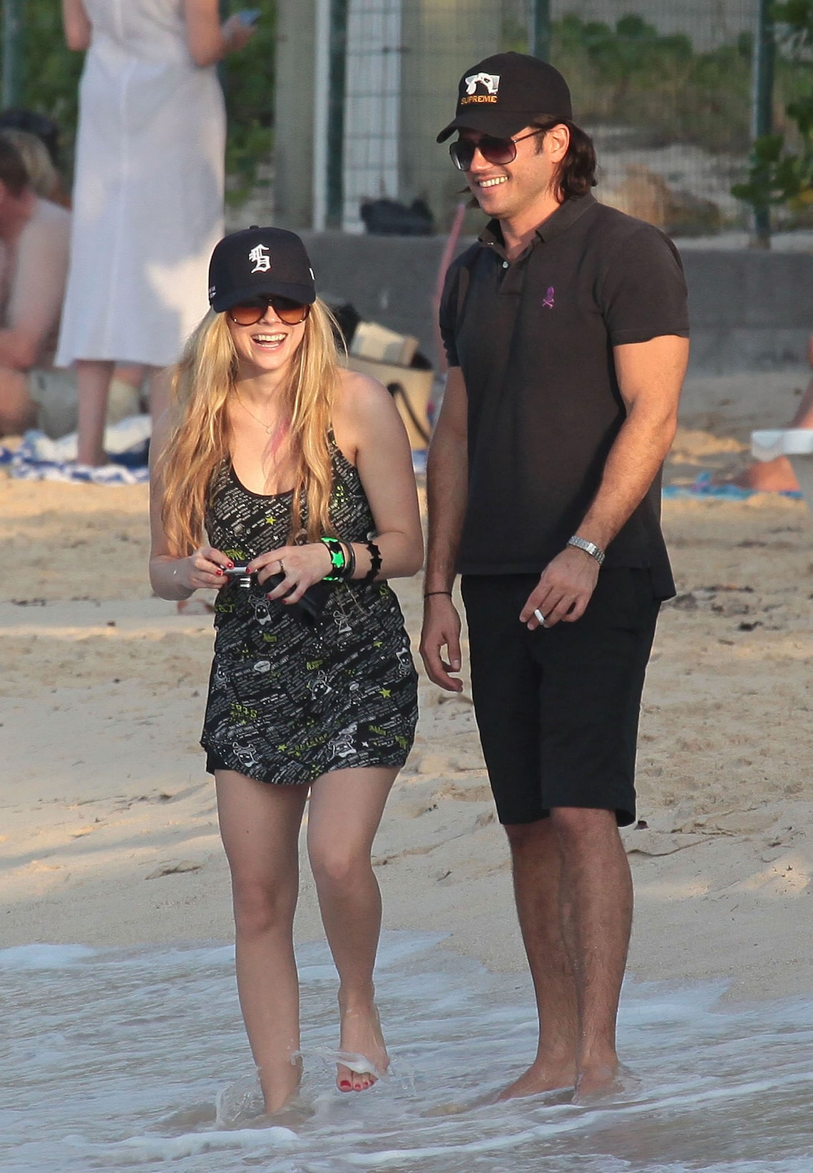 Avril Lavigne laughs while snapping photos with a male pal on the beach in St. Barts.