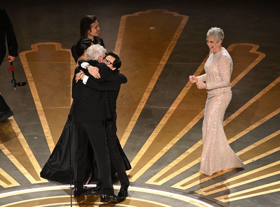 Ke Huy Quan hugs Harrison Ford as he celebrates winning the Oscar for Best Picture for "Everything Everywhere All at Once" onstage during the 95th Annual Academy Awards.